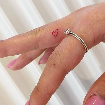 Татуировка love на пальце женской руки, фотография